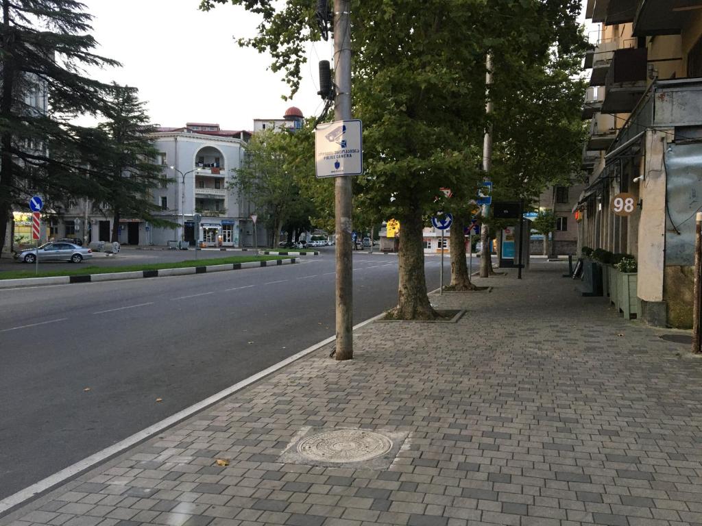 an empty street with trees and a street sign on a pole at Room 27 in Kutaisi in Kutaisi
