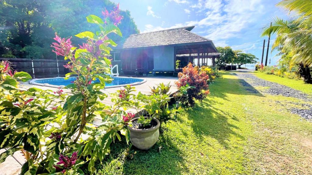 a garden with a building and flowers in front of it at RAIATEA - Orion Pool Bungalow in Uturoa