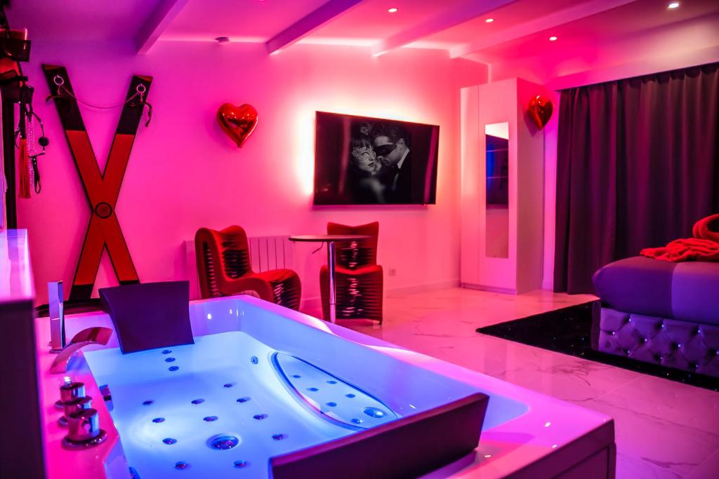 Cette chambre rose comprend une baignoire et un lit. dans l'établissement SECRET SUITE "Mr Grey" - Jacuzzi privatif - Gare RER C - Proche Paris, à Brétigny-sur-Orge
