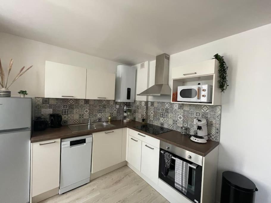 a kitchen with white cabinets and a sink and a microwave at T2 refait à neuf sur le thème oriental in Rodez