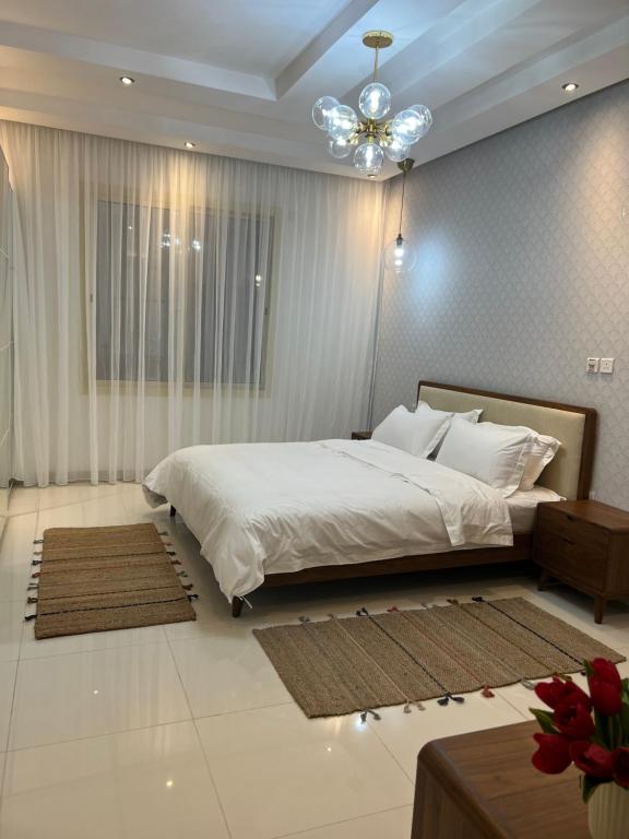 Un dormitorio con una gran cama blanca y una lámpara de araña. en Loft 16, en Yeda
