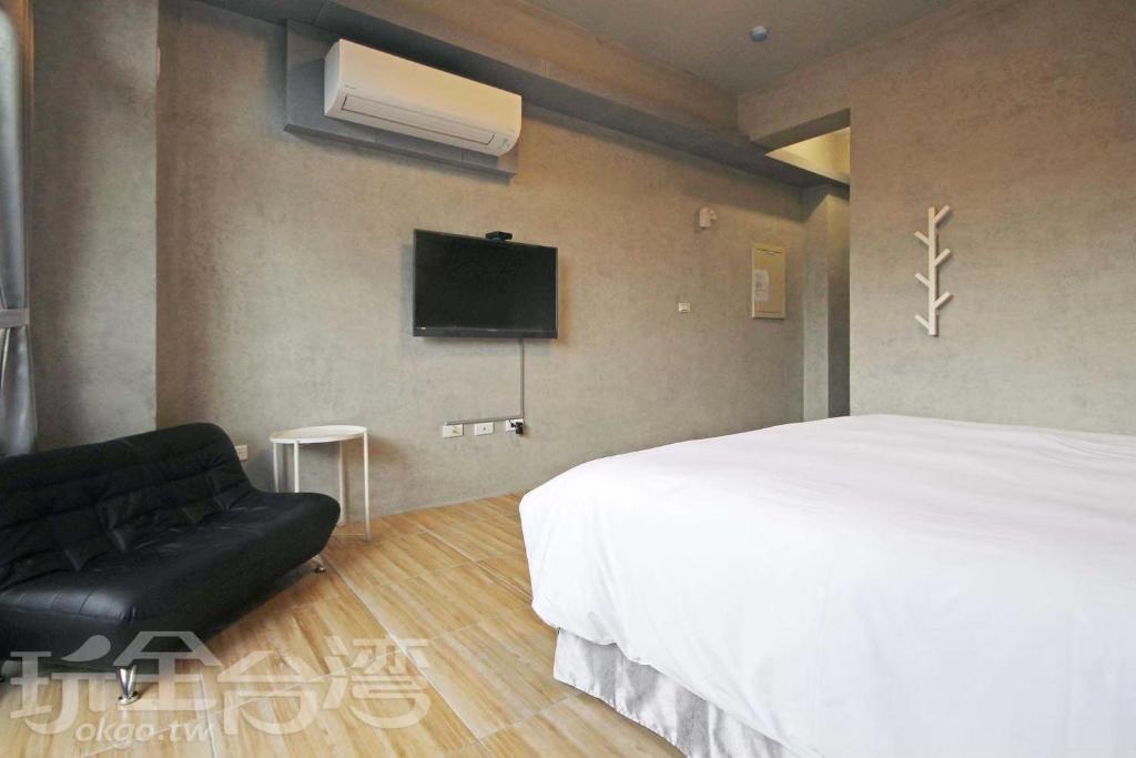 1 dormitorio con 1 cama y TV en la pared en Mei Jen house B&B 日月潭民宿, en Yuchi