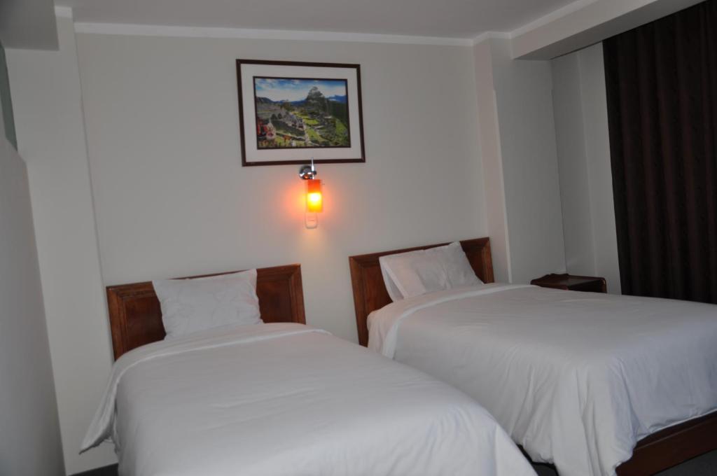 Habitación de hotel con 2 camas y una foto en la pared en CESAR'S HOTEL PERU, en Puno