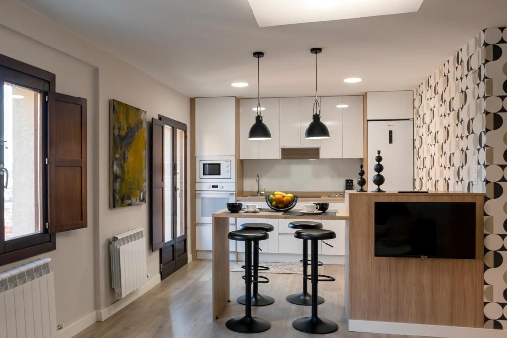 a kitchen with a island with bar stools at El Arco San Esteban by Unique Rooms in Burgos