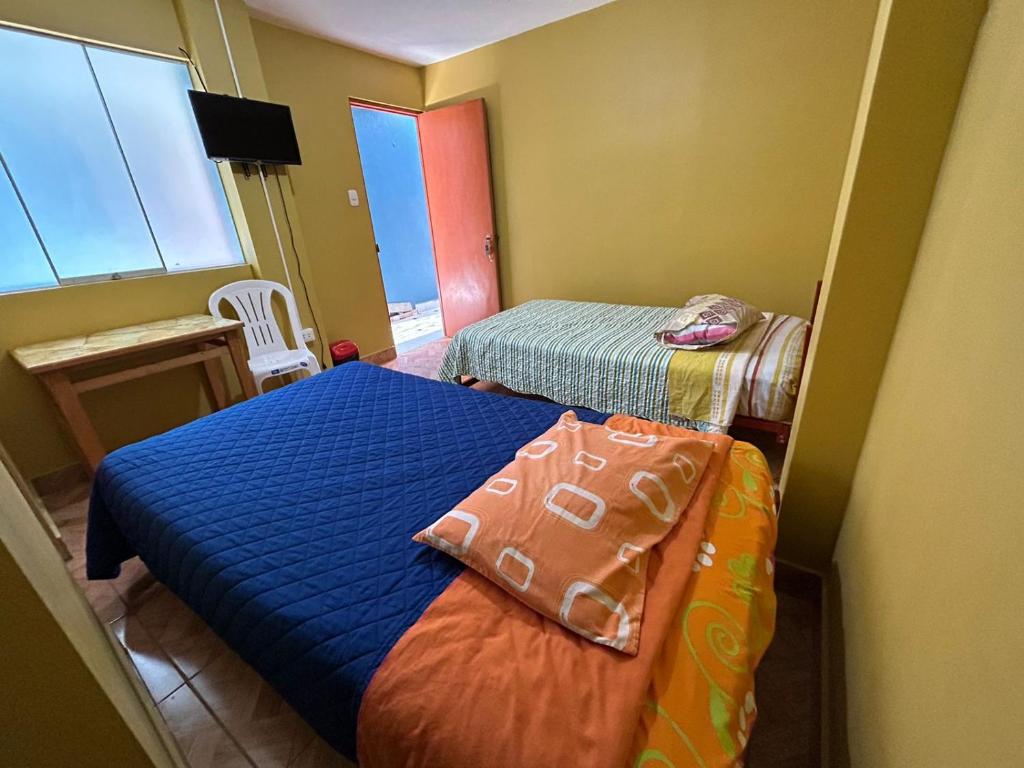 Habitación pequeña con 2 camas y ventana en Hostal EL TAMBO en Ica