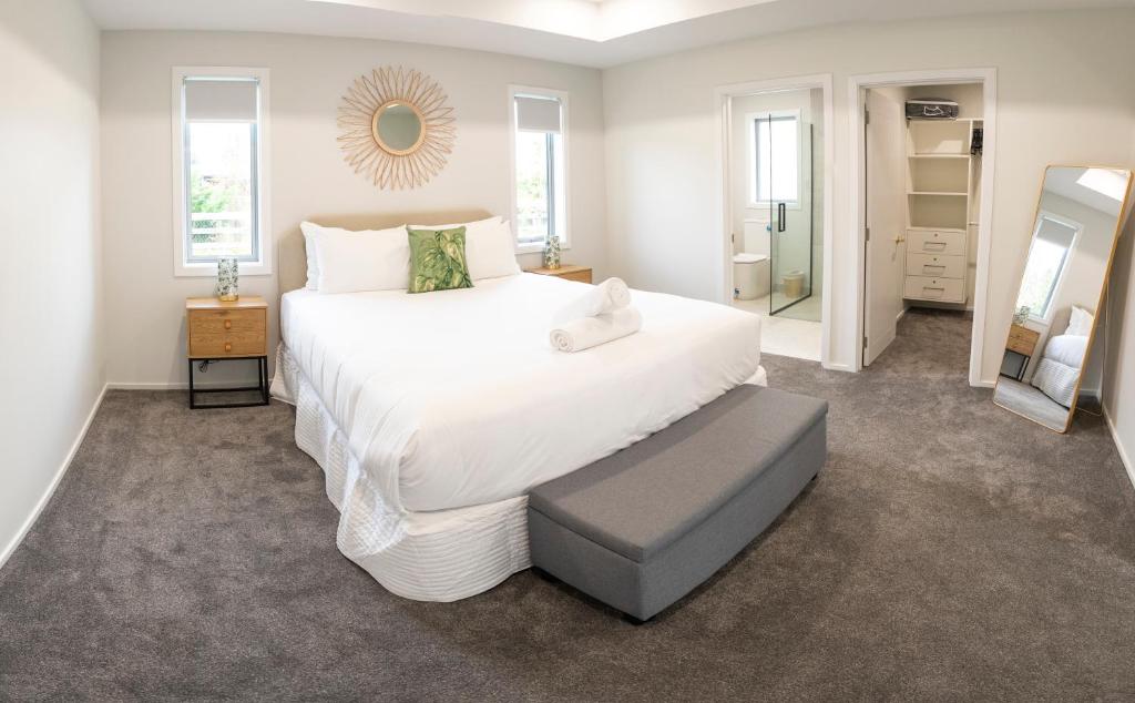 a bedroom with a large white bed and a mirror at Boundary Retreat Twizel in Twizel