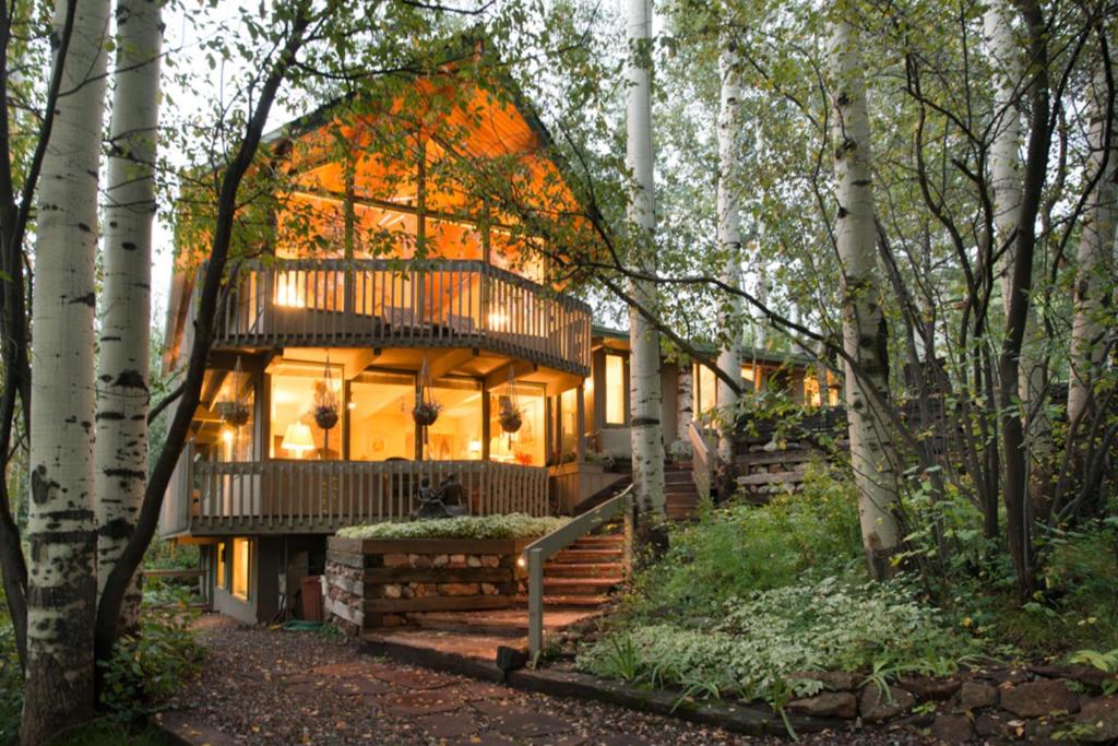 a tree house with a deck in the woods at Elegant Lodge with Hot Tub Walk to Highland Lifts in Aspen