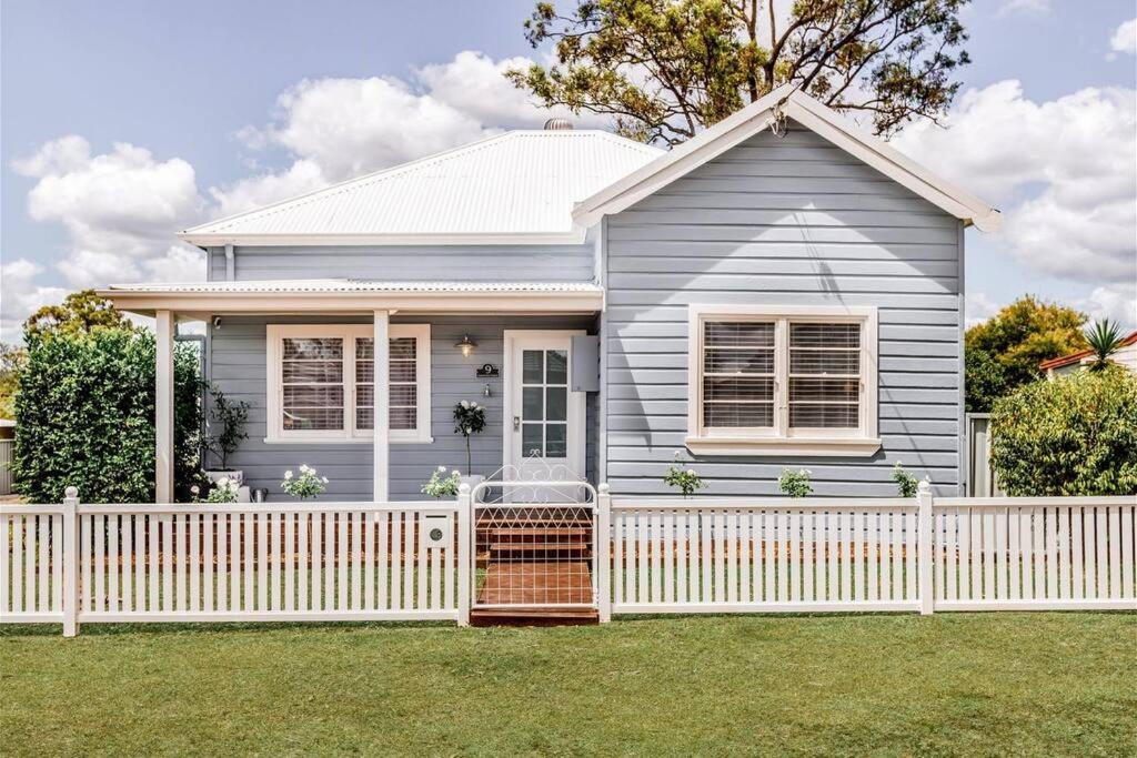 a small grey house with a white fence at Hamptons House on Hunter with fire pit in Aberdare