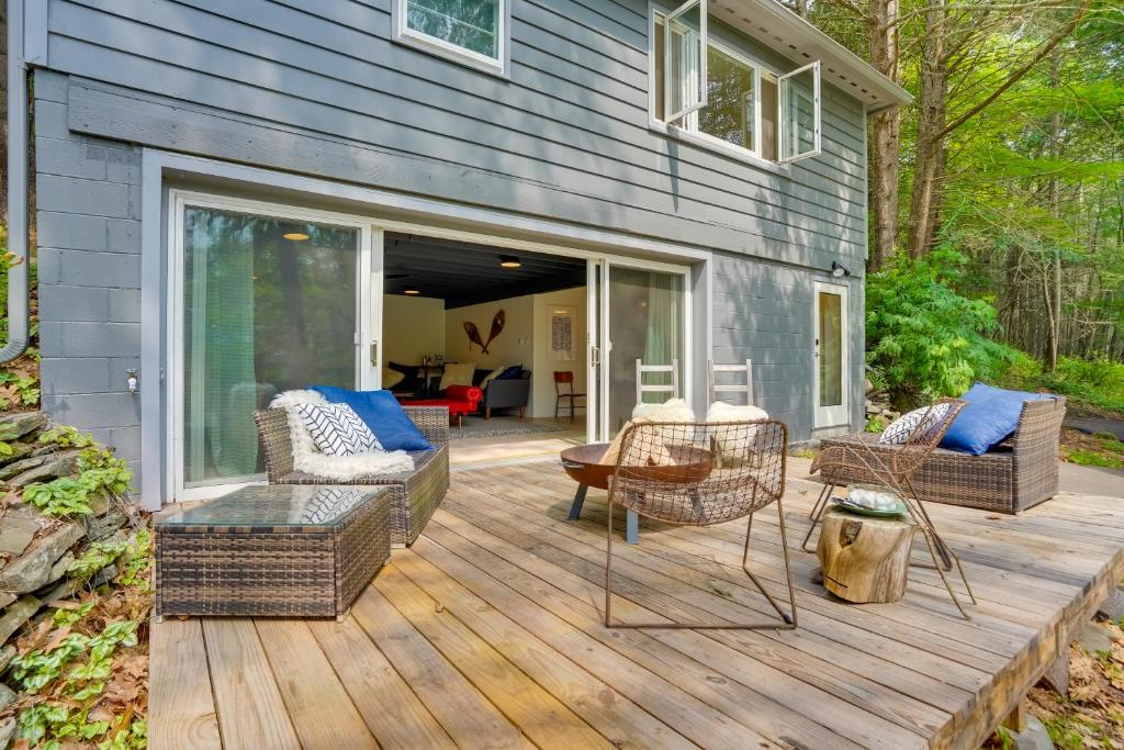een patio met rieten stoelen en tafels op een houten terras bij Modern Mountainside Home with Trail Access On-Site in Boiceville
