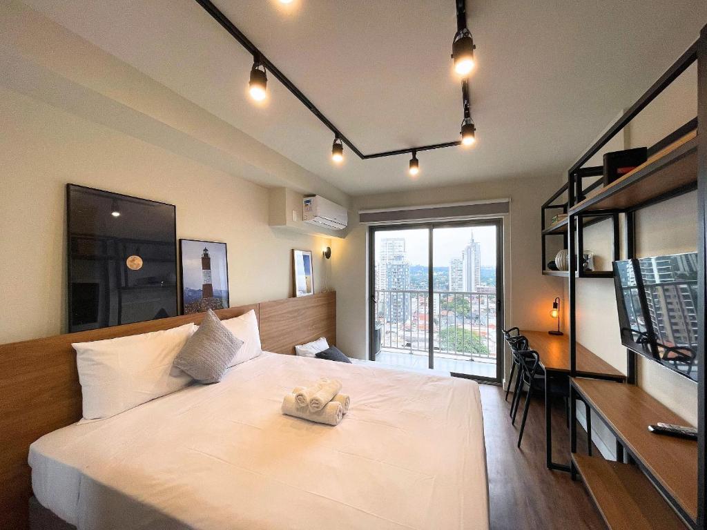 Un dormitorio con una gran cama blanca y una ventana en Houx Pinheiros en São Paulo
