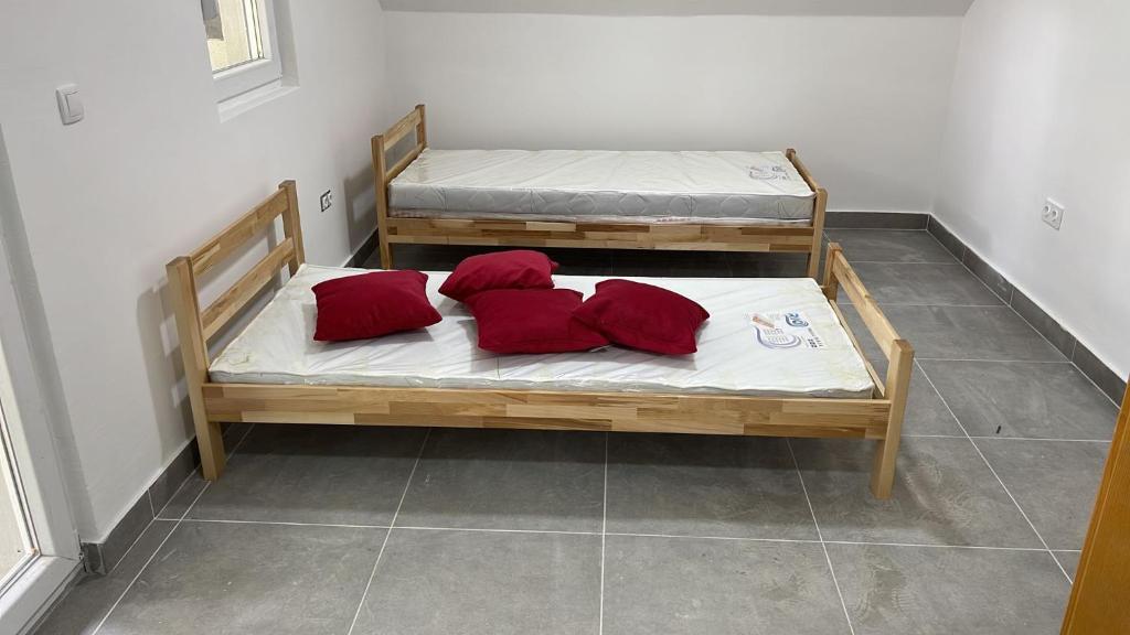 two beds with red pillows on them in a room at Bosnia GCC in Vinogradi