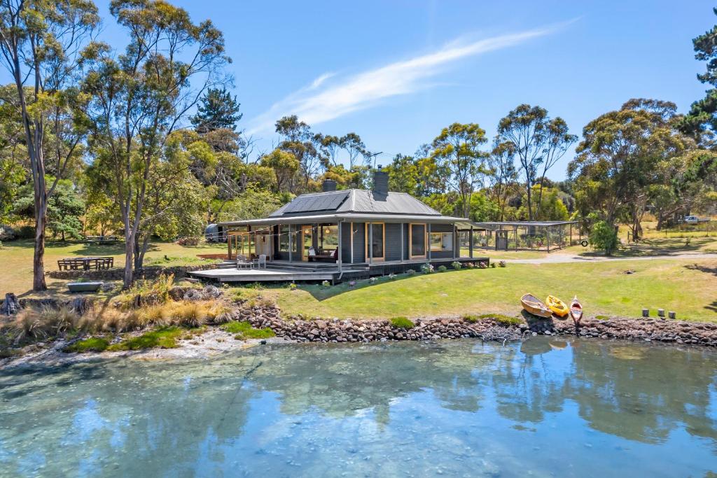 une maison avec une rivière devant elle dans l'établissement 'Questa' Heritage Cottage, à Barnes Bay