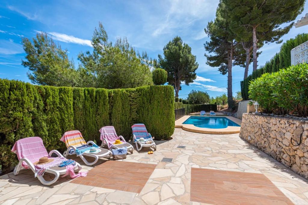 - un groupe de trois chaises à côté d'une piscine dans l'établissement Villa Rosario - PlusHolidays, à Calp