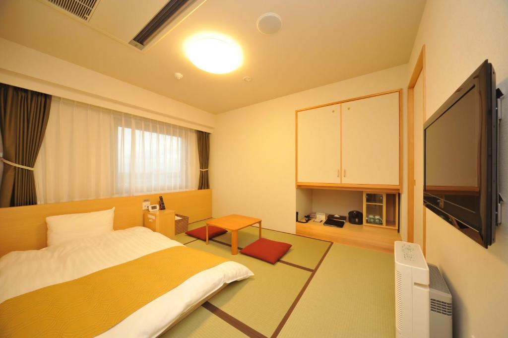 a bedroom with a bed and a tv in it at Dormy Inn Obihiro in Obihiro