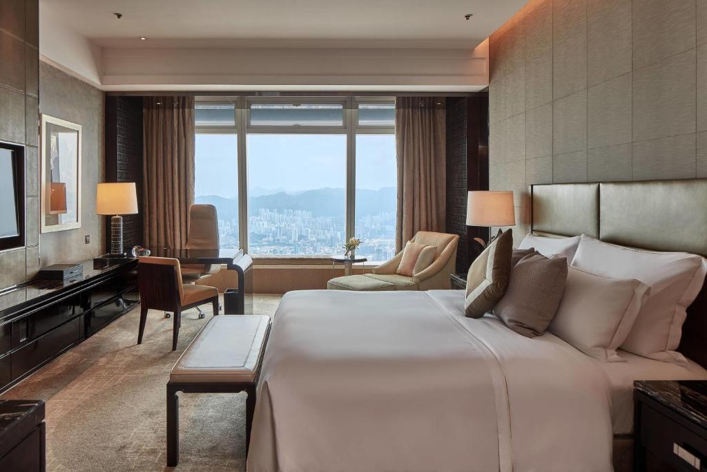 een hotelkamer met een groot bed en een bureau bij The Ritz-Carlton Hong Kong in Hong Kong