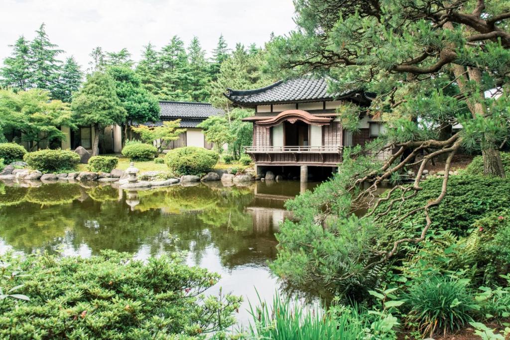 een tuin met een huis en een vijver bij Tanakaya in Kurobe