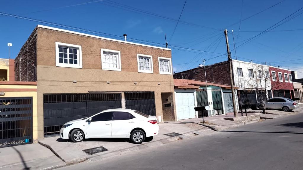 un coche blanco estacionado frente a un edificio en Hermoso departamento amoblado! en Mendoza