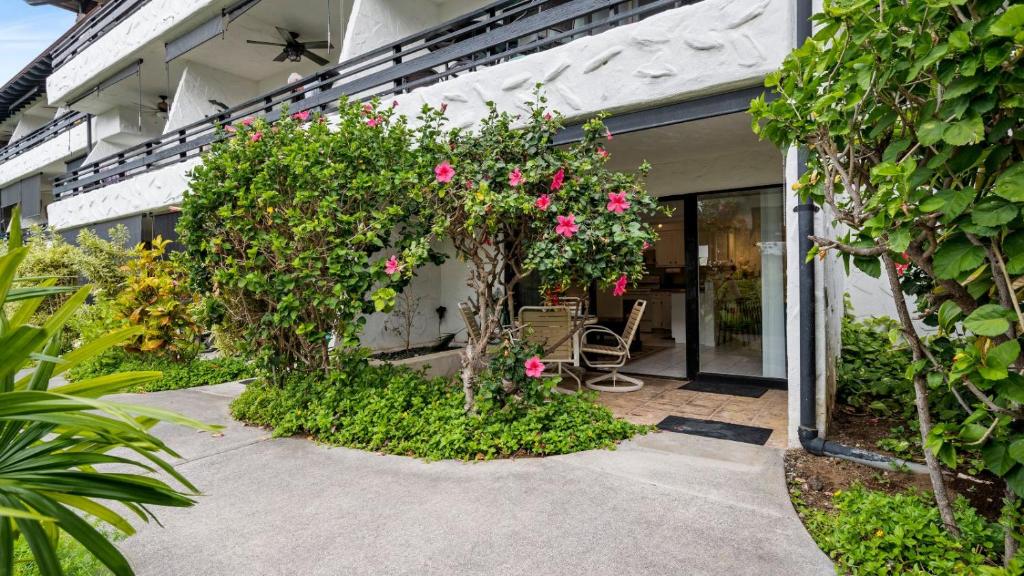 una casa con flores rosas y un patio en Casa de Emdeko 121, en Kailua-Kona