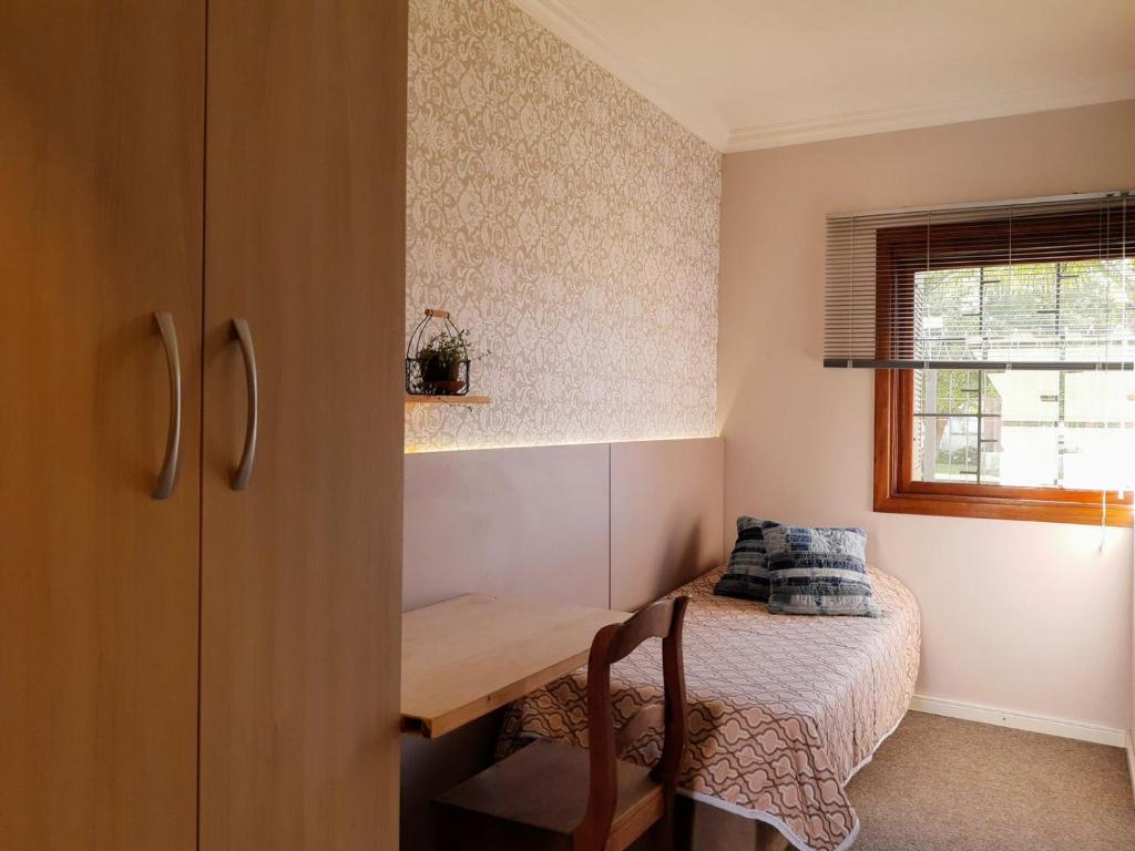 a small room with a table and a bed at Moradia Compartilhada Pelotas in Pelotas