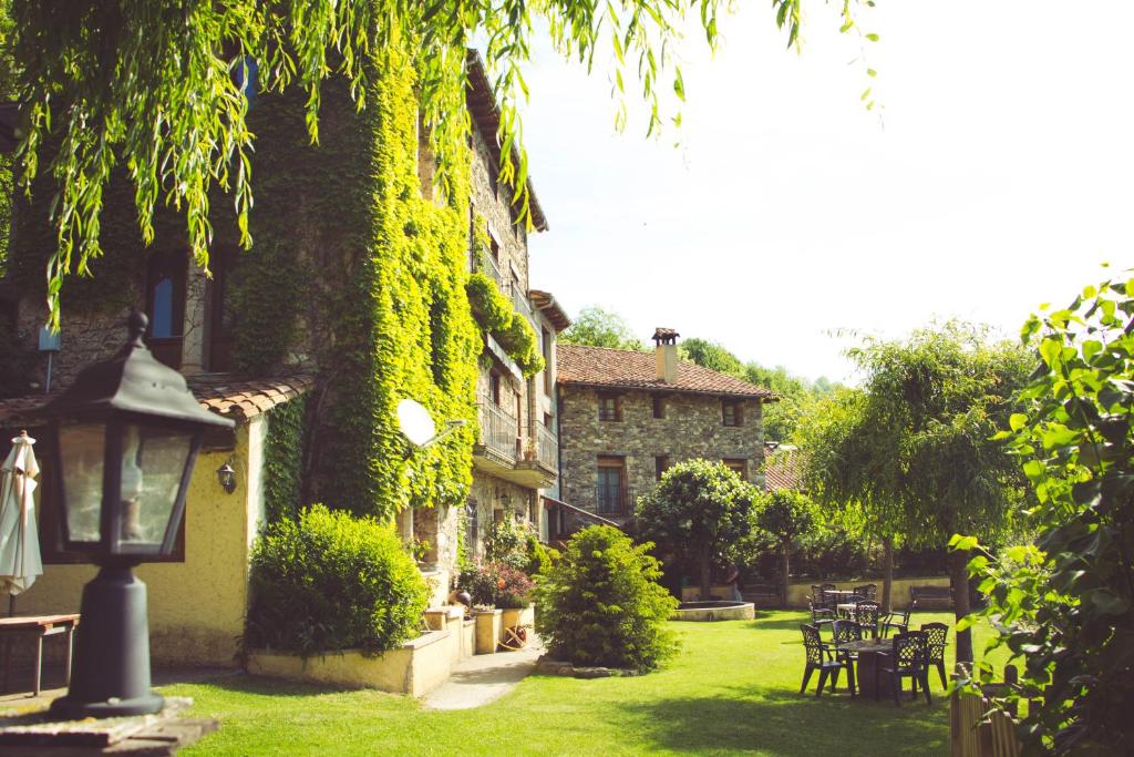 a building covered in green ivy with tables and chairs at Casa Etxalde in Camprodon