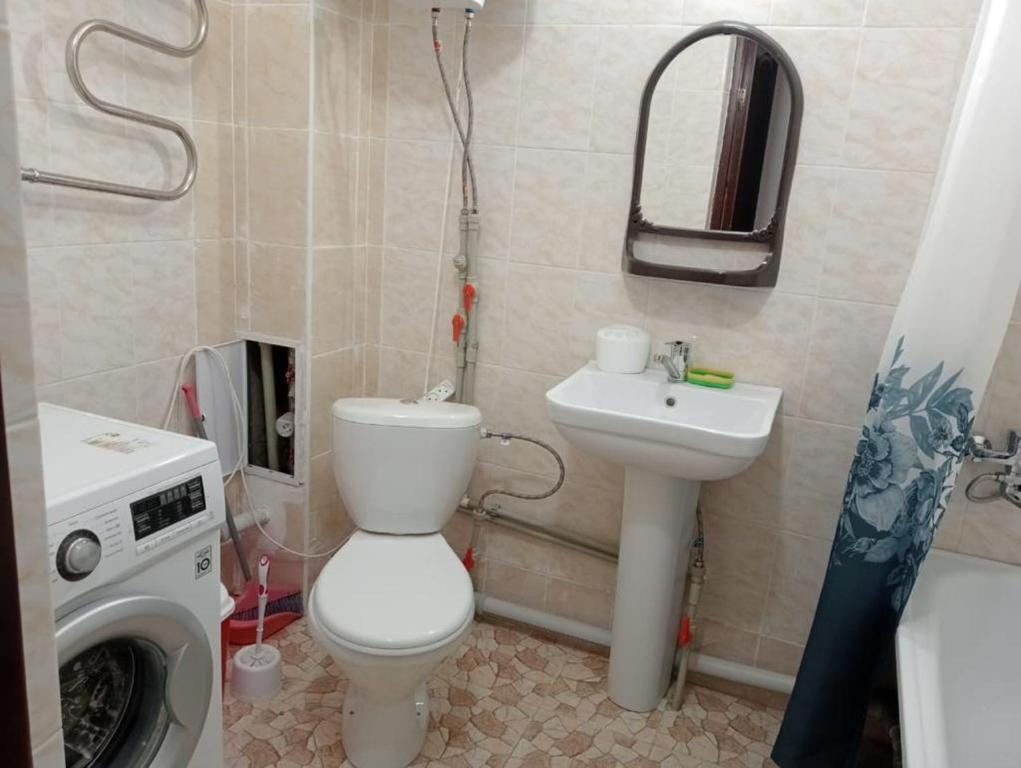 y baño con aseo, lavabo y lavadora. en Квартиры Уют в Туркестане, en Türkistan