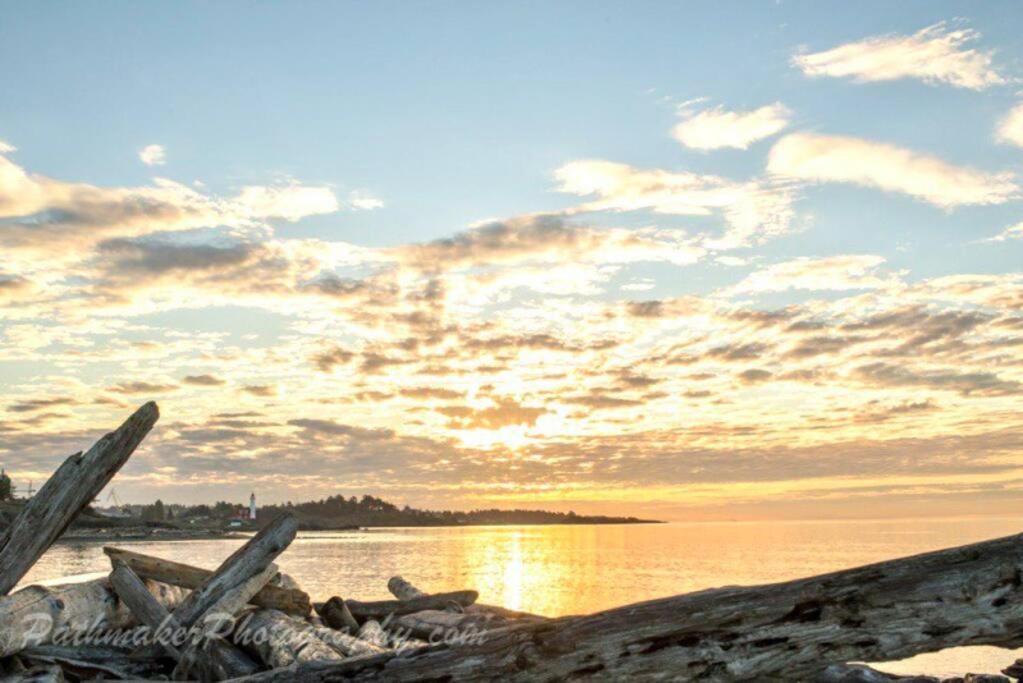 een zonsondergang boven het water met rotsen op een strand bij Esquimalt Lagoon Life in Victoria