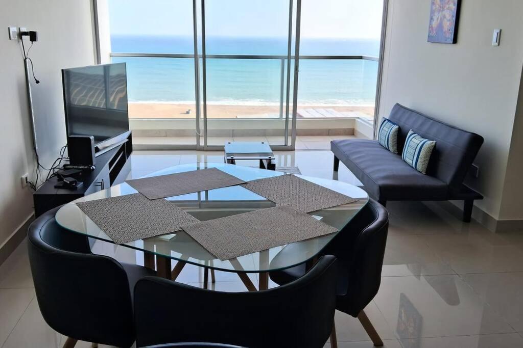 sala de estar con mesa de cristal y sillas en apartamento de estreno con balcón frente al mar., en Lima