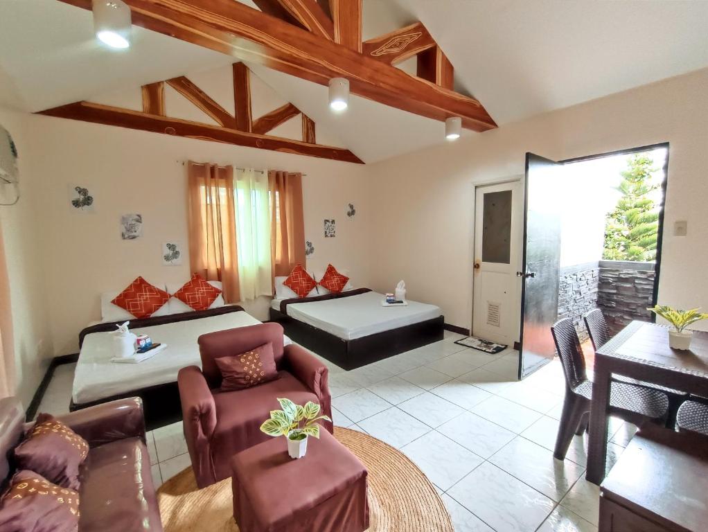 a bedroom with two beds and a living room at La Gracia Apartelle in Tagaytay