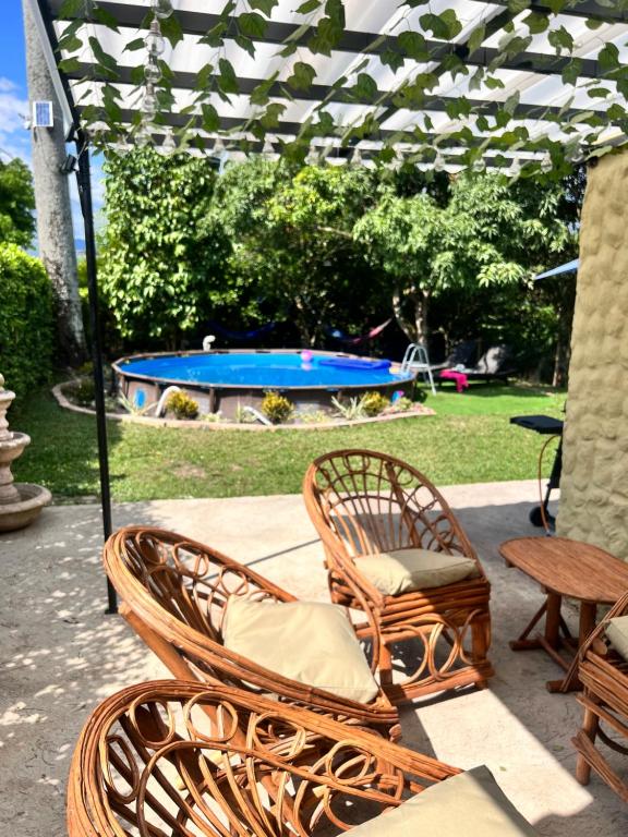 Duas cadeiras de vime, uma mesa e uma piscina. em Casa de campo San Juan del Puente en Villeta em Villeta