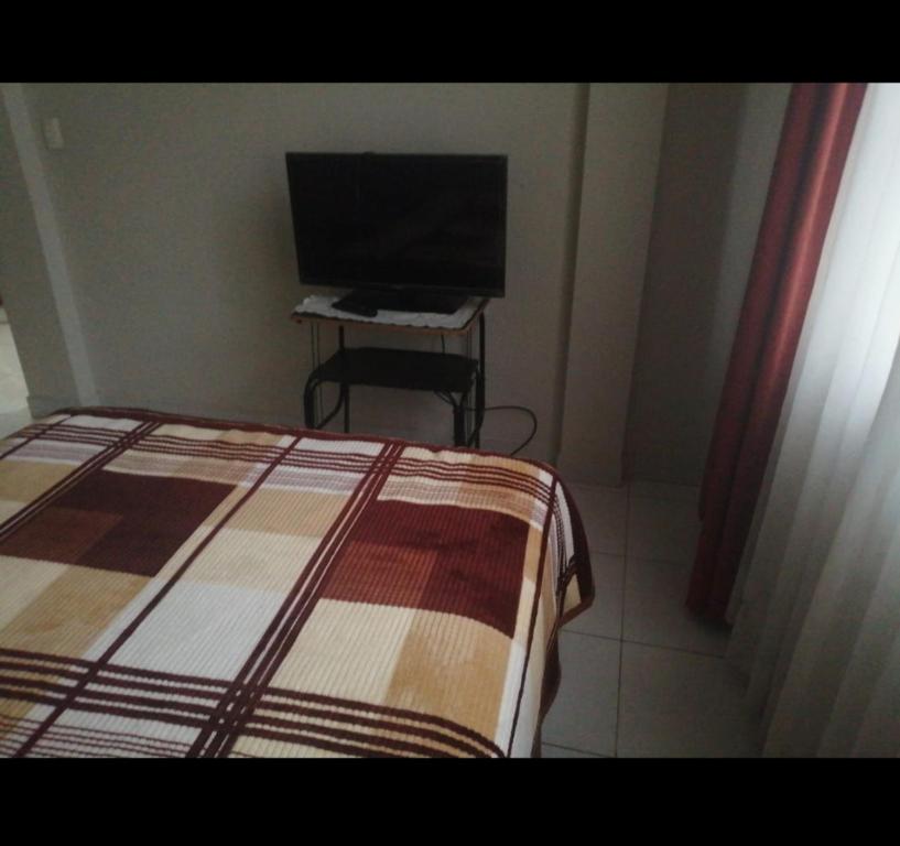 ein Schlafzimmer mit einem Bett und einem TV auf dem Tisch in der Unterkunft Departamento céntrico a 4 cuadras de la Plaza principal in Sucre