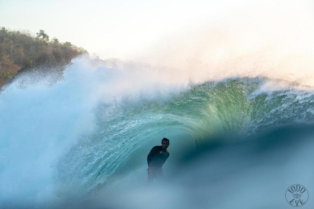 a man is standing inside of a wave at Medewi Secret SurfCamp in Pulukan