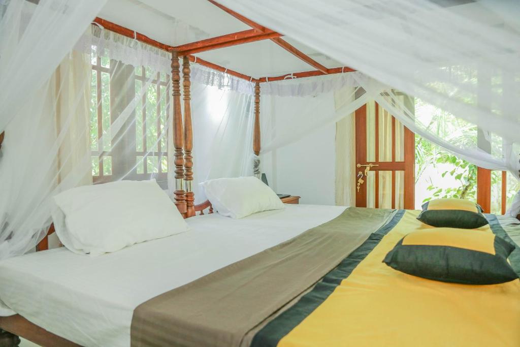 Schlafzimmer mit einem großen Bett und weißen Vorhängen in der Unterkunft Shady Cottage in Ahangama