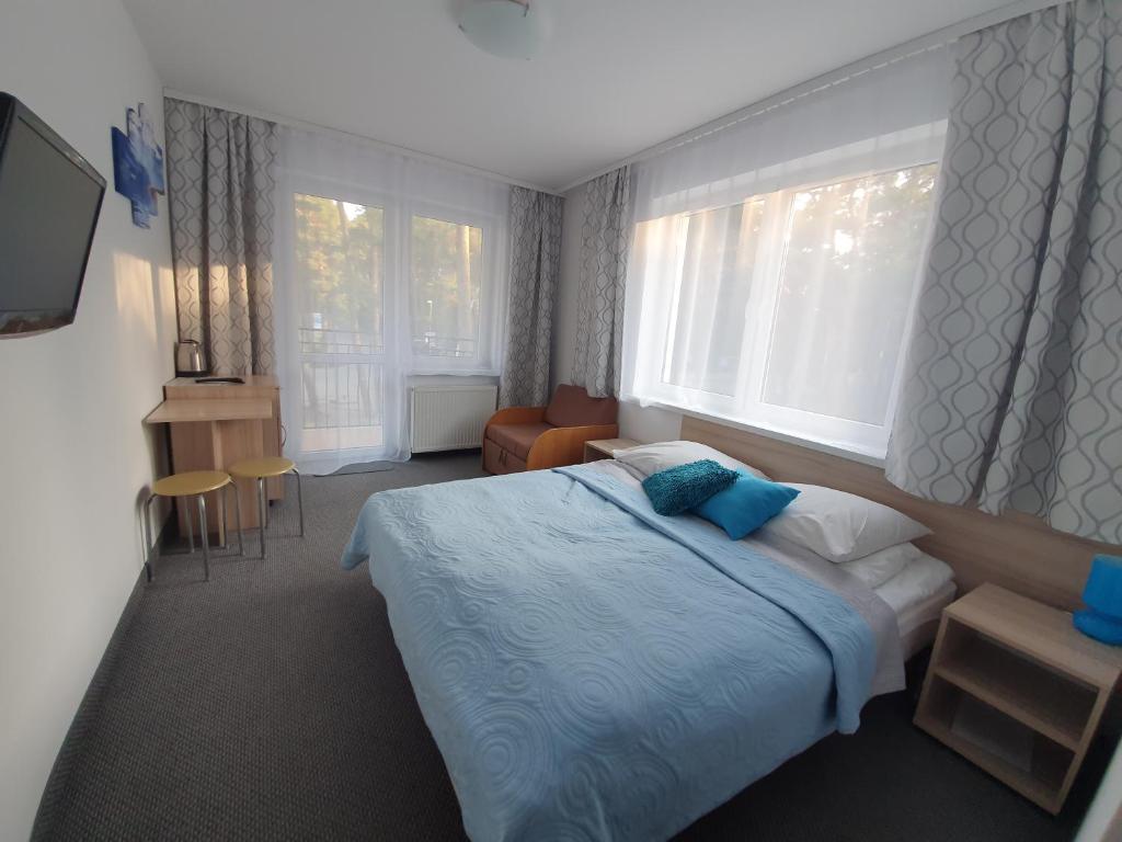 Schlafzimmer mit einem Bett, einem Stuhl und Fenstern in der Unterkunft The White House Dom Wypoczynkowy in Pogorzelica