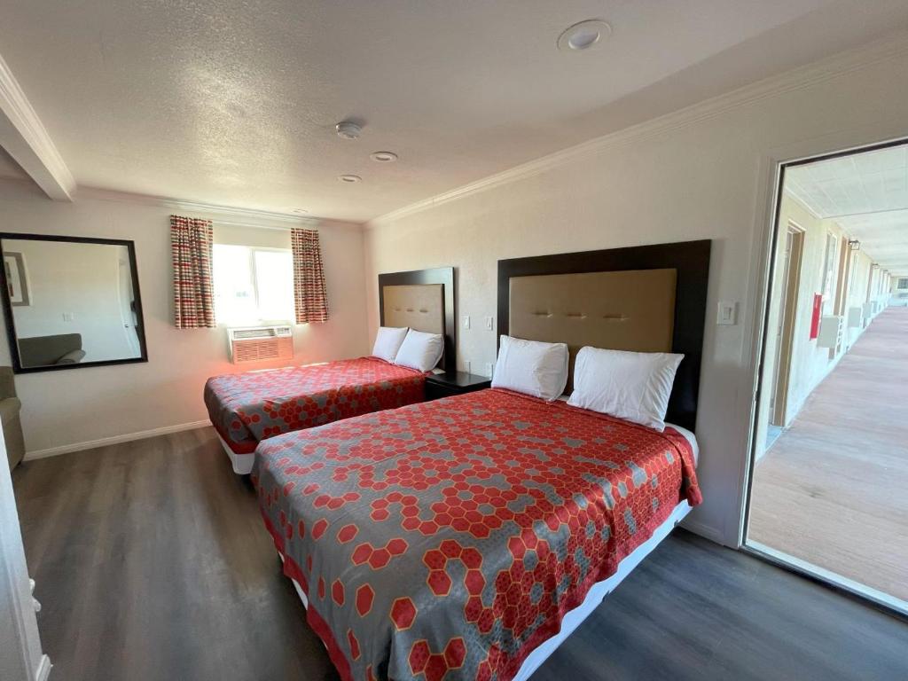 Habitación de hotel con 2 camas y espejo en Palm Inn en Mojave