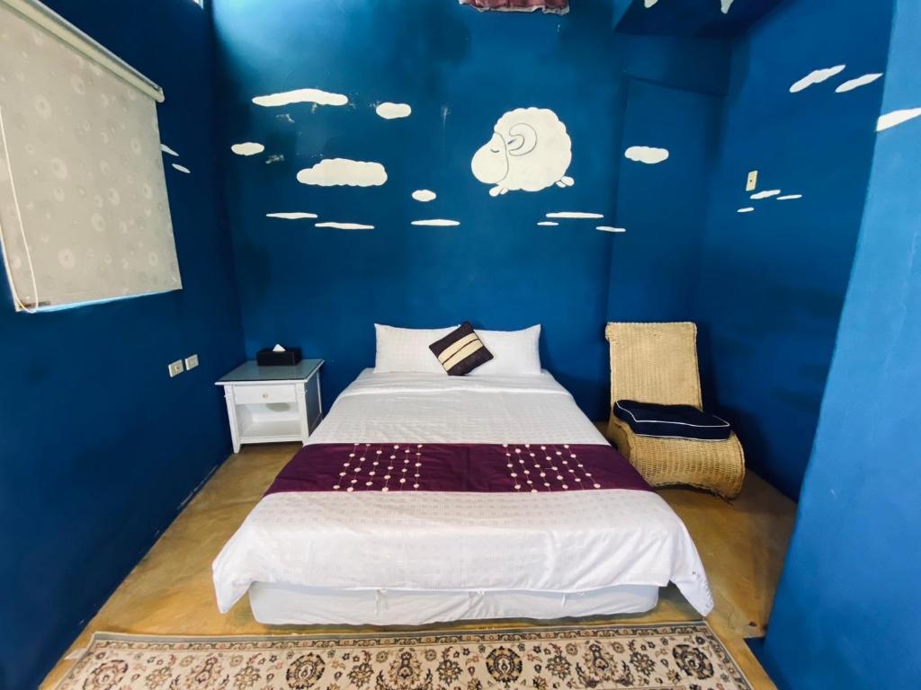 Dormitorio azul con cama con nubes en la pared en Lazy Sheeps Hostel, en Hengchun