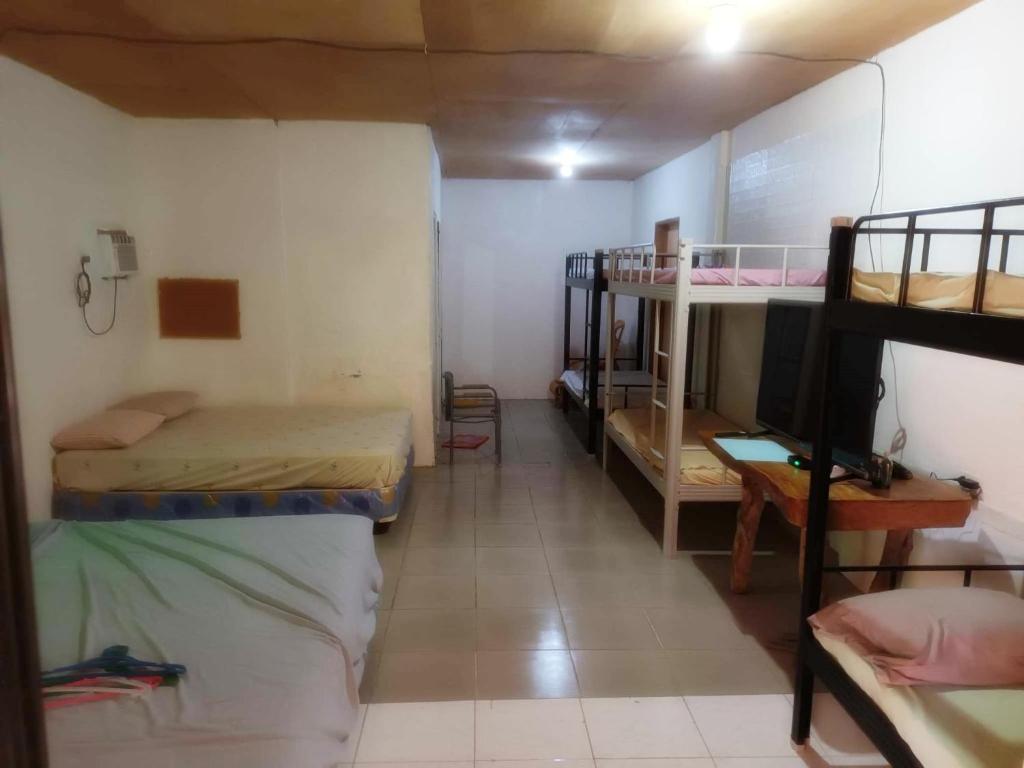 a room with three bunk beds and a television at Villagracia HomeStay 