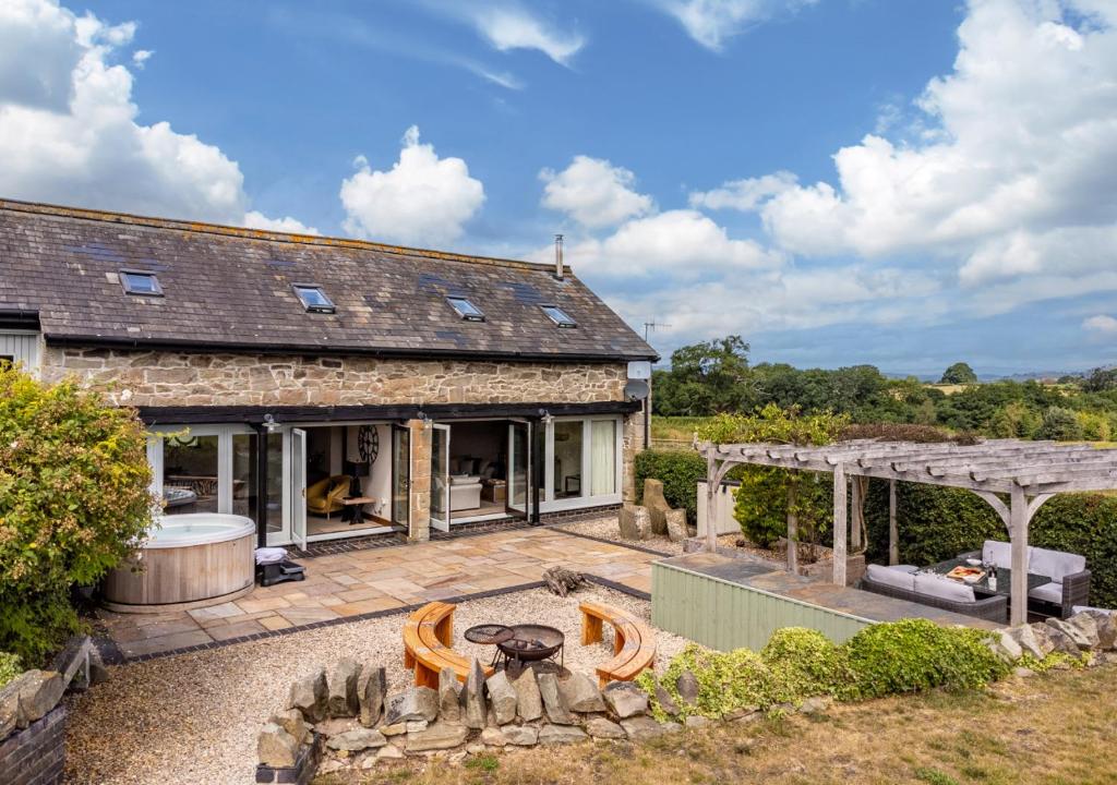 an external view of a stone house with a fire pit at Camlad Barn in Chirbury