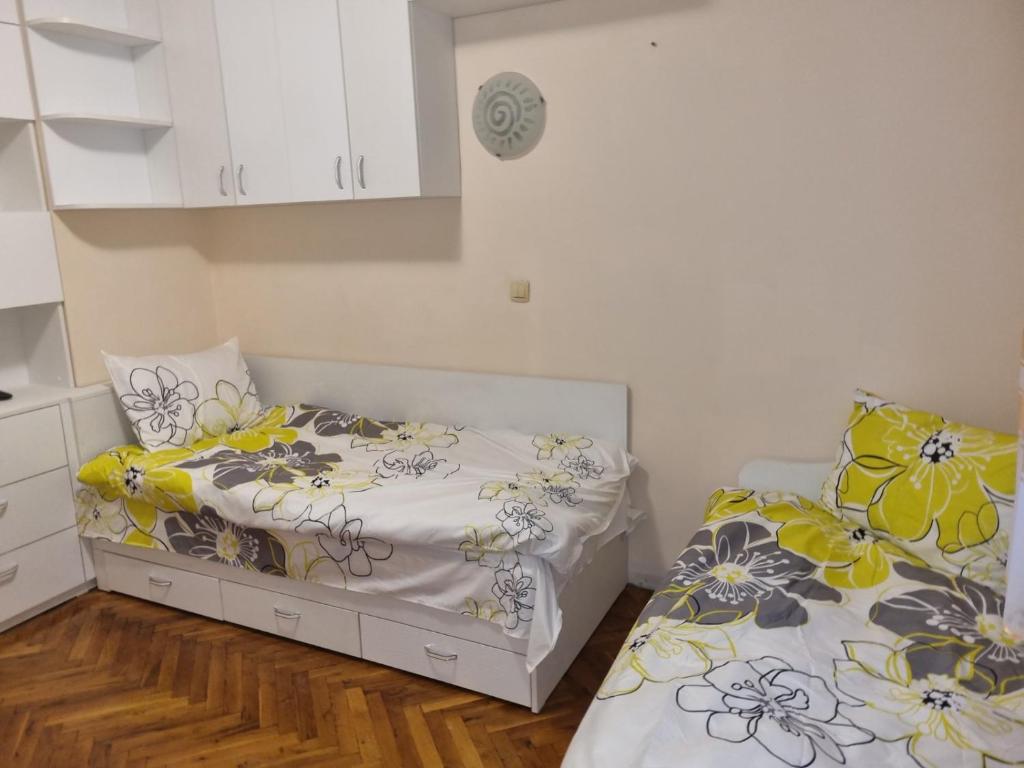two beds in a small room with white cabinets at Teodora Apartment in Ruse