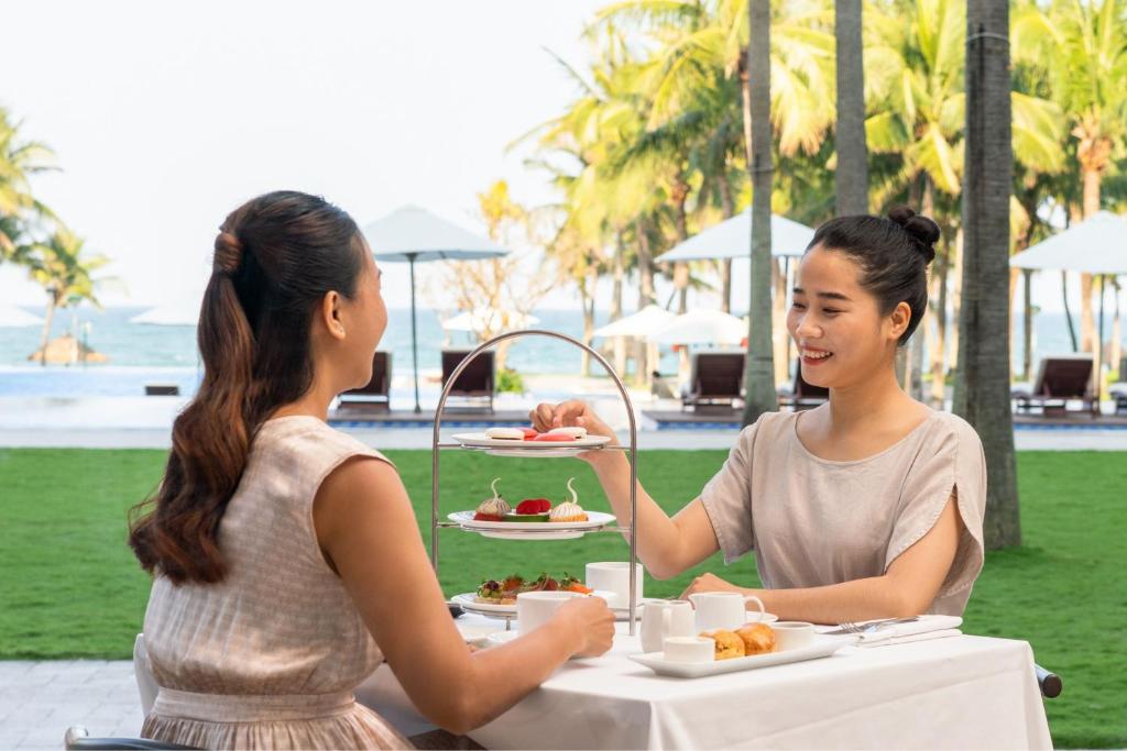 An outdoor breakfast table beside a lawn, pool and palm-lined resort grounds.