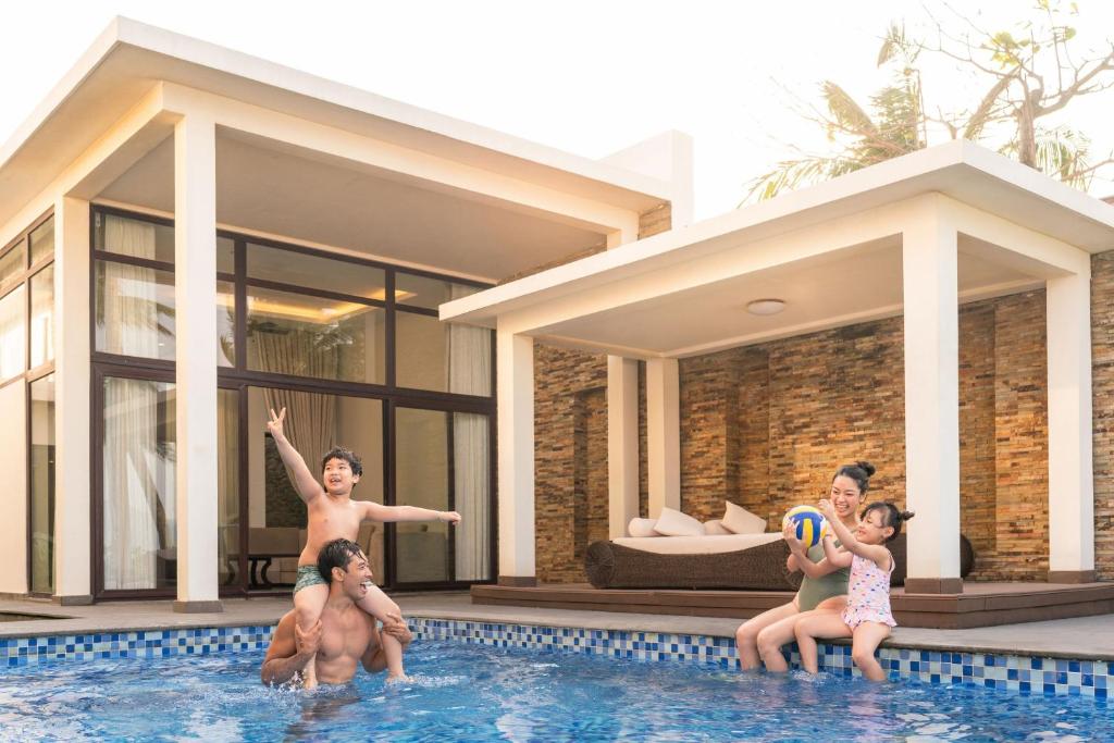 A private villa pool sits beside a covered outdoor lounge and tall glass doors.