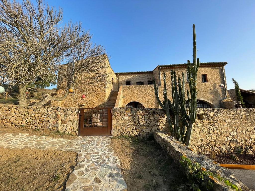 un bâtiment avec un cactus à côté d'un mur de pierre dans l'établissement Can Clarós, à Capmany