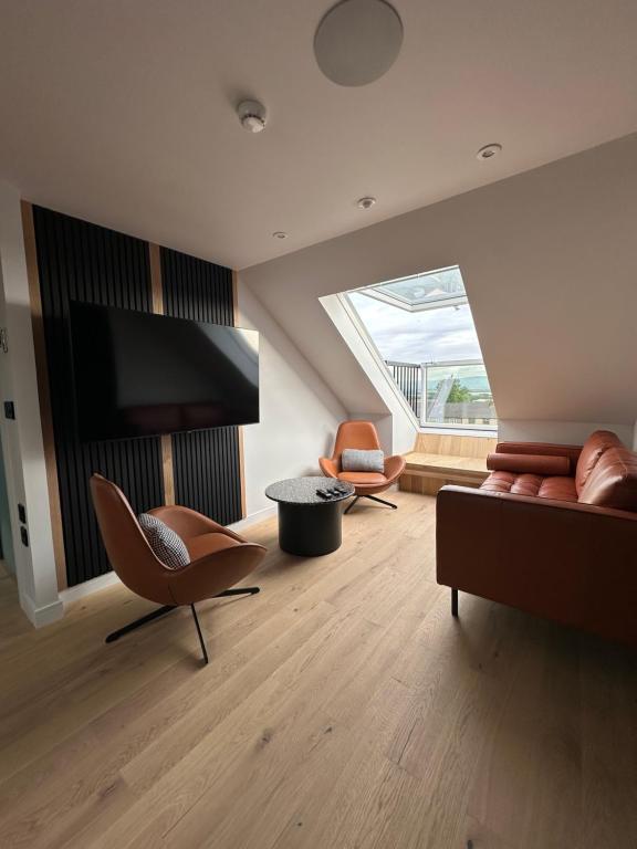 a living room with a couch and chairs and a tv at Laurieston Penthouse 