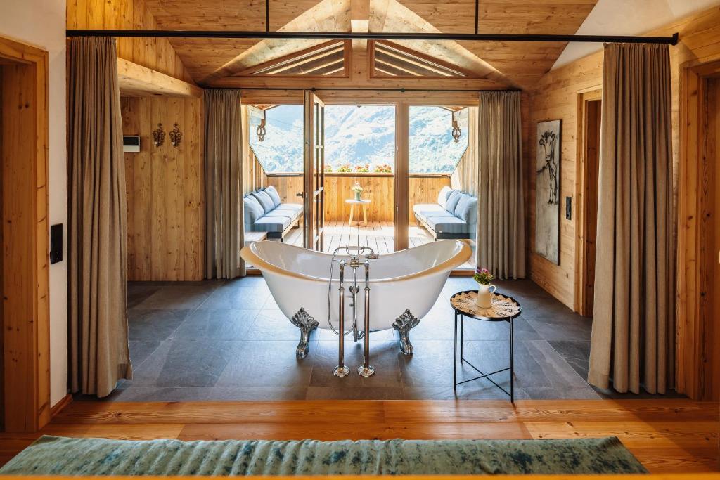 a bath tub in a room with a large window at Fürthermoar Hideaways in Kaprun