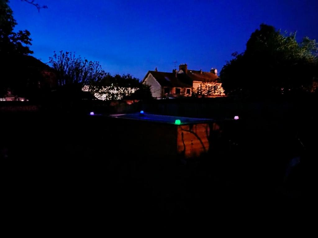 a swimming pool at night with a house in the background at Chez Aurélia - Chambres &amp; Table d&#39;hôtes in La Couture-Boussey