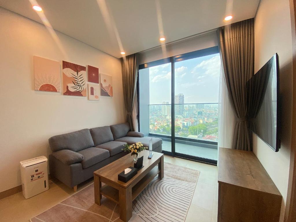 een woonkamer met een bank en een groot raam bij Lancaster Luminaire Apartment Hotel in Hanoi