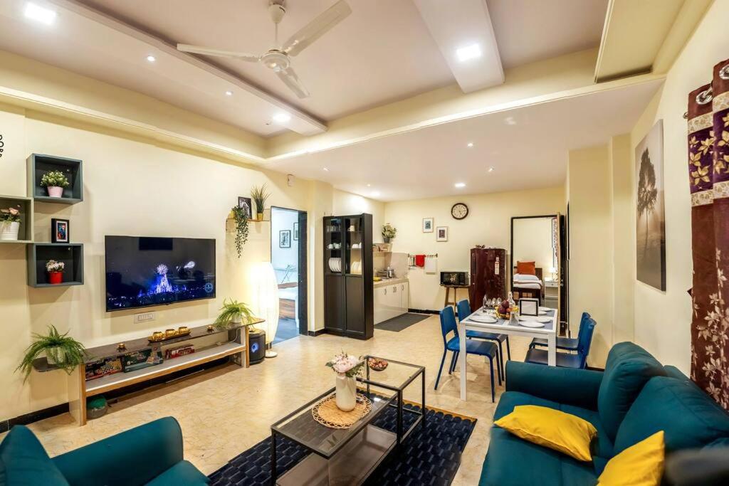 un soggiorno con divano blu e TV di The Banyan Tree Adobe a Kolhapur