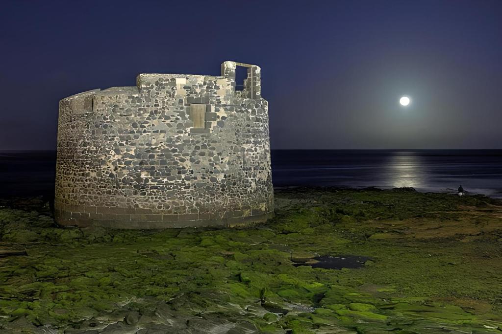 un vecchio edificio in pietra sulla spiaggia di notte di Casa La Calma a Las Palmas de Gran Canaria