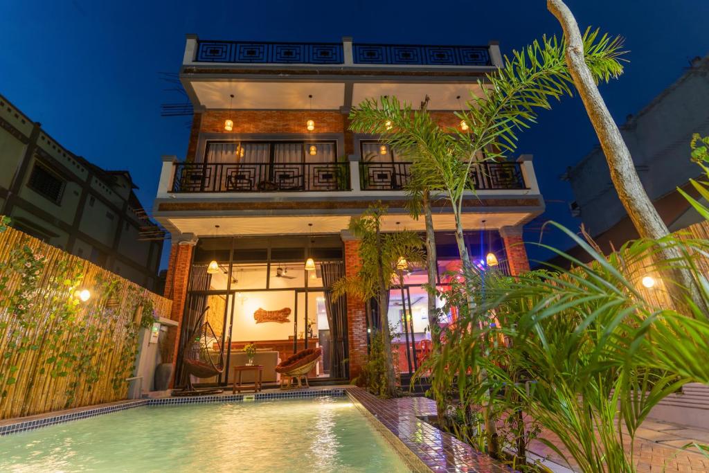 uma casa com piscina em frente a um edifício em Angkor Rithy Residence 2 em Phumĭ Réach Born (1)