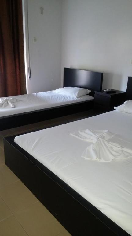 two beds in a hotel room with white sheets at Philippos & Maria Apartments in Paralia Katerinis