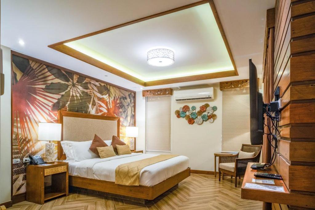 um quarto de hotel com uma cama e uma televisão em La Jolla Luxury Beach Resort em Malawin